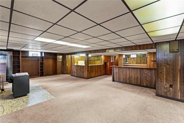 below grade area with carpet floors, wood walls, and a paneled ceiling