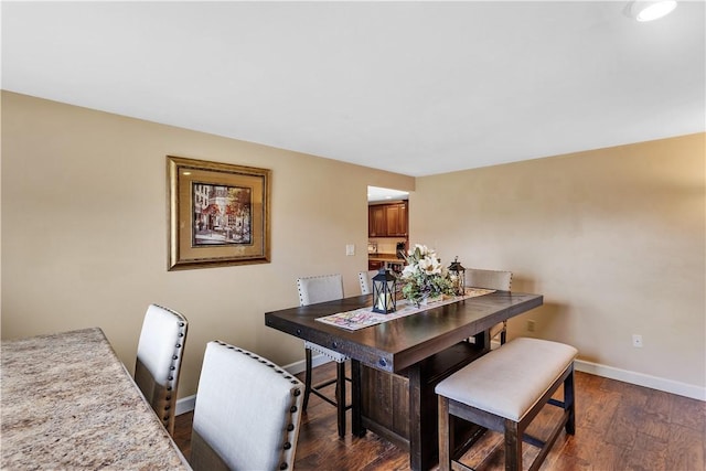 dining area with baseboards and dark wood finished floors