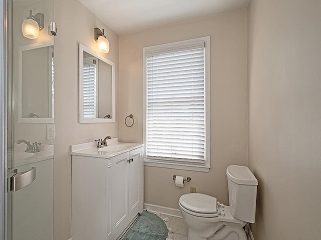 bathroom with a healthy amount of sunlight, baseboards, vanity, and toilet