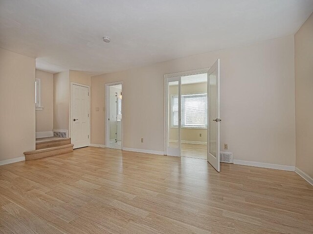 spare room featuring visible vents, baseboards, stairway, and light wood-type flooring