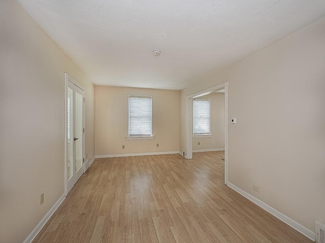 unfurnished room with baseboards and light wood-style flooring
