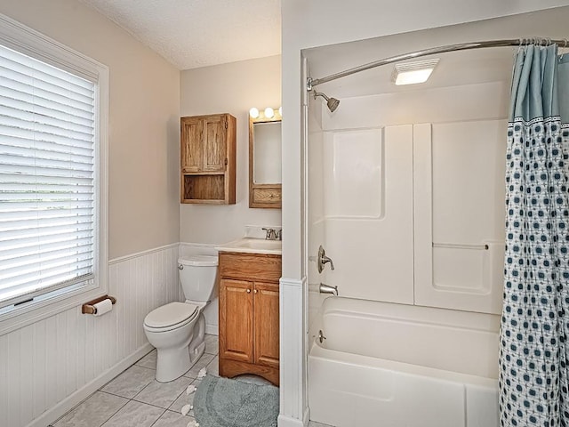 full bathroom with wainscoting, vanity, shower / bath combo with shower curtain, toilet, and tile patterned floors