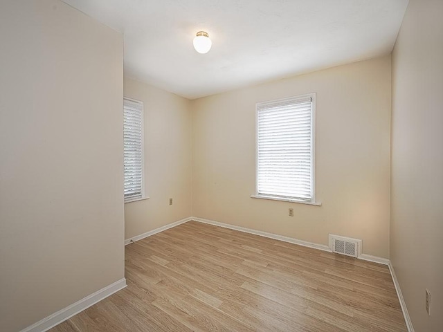 unfurnished room with baseboards, visible vents, and light wood-style floors