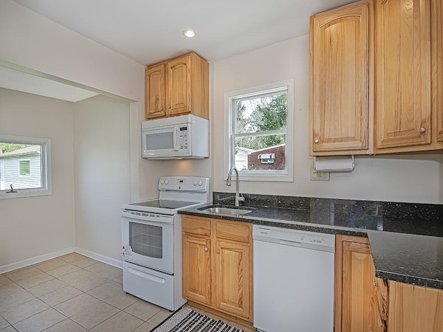 kitchen featuring white appliances, a wealth of natural light, a sink, and dark stone countertops