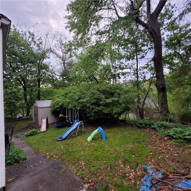 view of yard featuring a storage unit, a playground, and an outbuilding