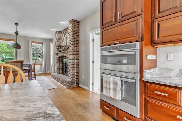 6181 Brown Rd, Penn Twp, PA 16002 - kitchen with double oven, light wood-style floors, a fireplace, decorative light fixtures, and brown cabinetry