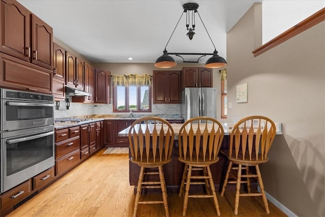 6181 Brown Rd, Penn Twp, PA 16002 - kitchen featuring stainless steel appliances, a breakfast bar, light wood finished floors, tasteful backsplash, and recessed lighting