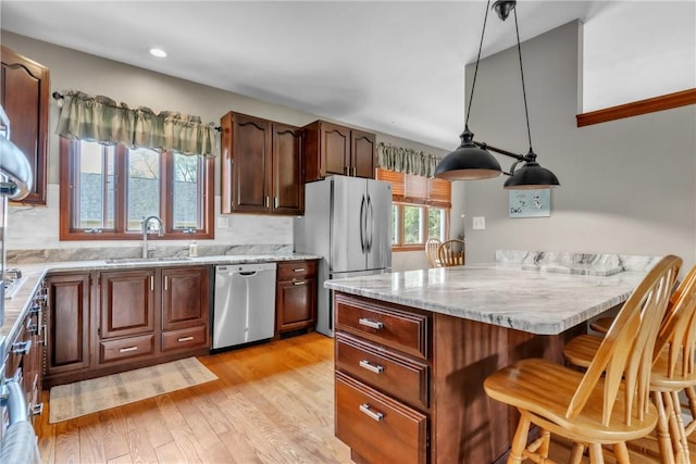 6181 Brown Rd, Penn Twp, PA 16002 - kitchen with stainless steel appliances, a breakfast bar area, light wood-type flooring, light stone counters, and hanging light fixtures
