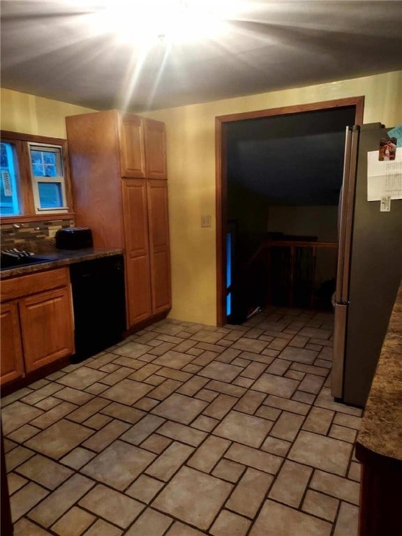 kitchen with brick floor, freestanding refrigerator, and black dishwasher