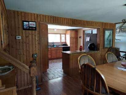 kitchen with brown cabinets, wood walls, a peninsula, wood finished floors, and refrigerator