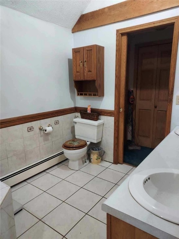 bathroom with tile walls, a baseboard heating unit, toilet, and a textured ceiling