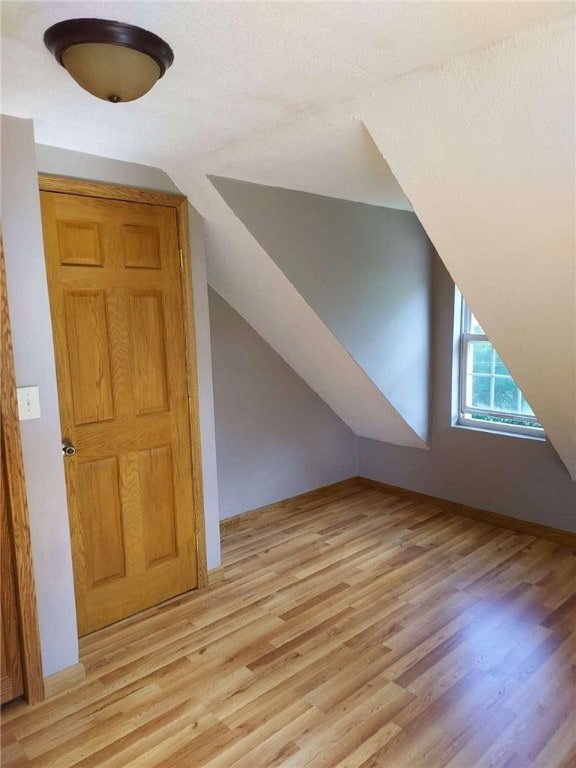 bonus room with light wood finished floors and lofted ceiling