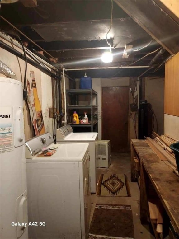 unfinished below grade area featuring washer and clothes dryer and electric water heater