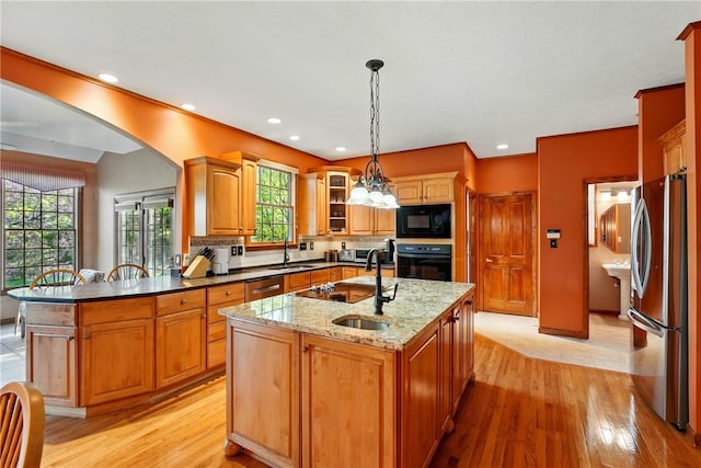 kitchen featuring a sink, black appliances, and light wood-style floors