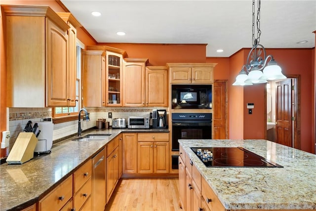 kitchen with a sink, light wood-style flooring, tasteful backsplash, glass insert cabinets, and black appliances