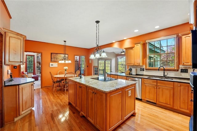 kitchen featuring a sink, light wood finished floors, decorative backsplash, stainless steel dishwasher, and a kitchen island