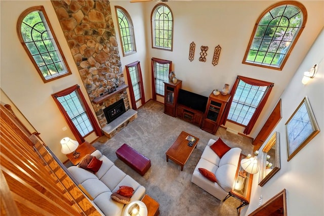 living room with baseboards, a high ceiling, carpet, and a stone fireplace