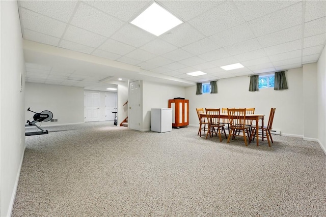 carpeted dining area with baseboards, stairs, and a paneled ceiling