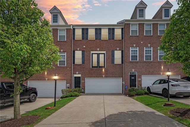 view of property with an attached garage, driveway, and brick siding