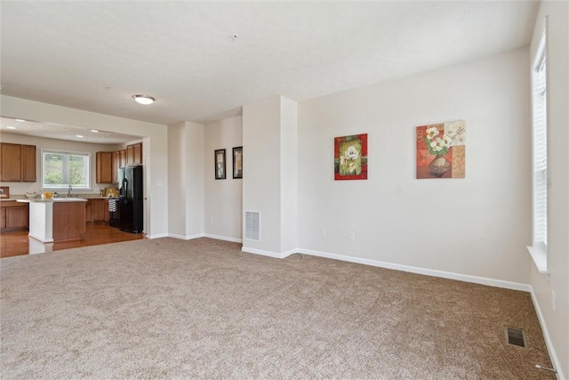 unfurnished living room with baseboards, carpet flooring, and visible vents