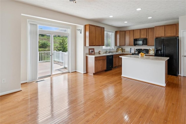 kitchen with brown cabinetry, recessed lighting, light countertops, light wood-style flooring, and black appliances
