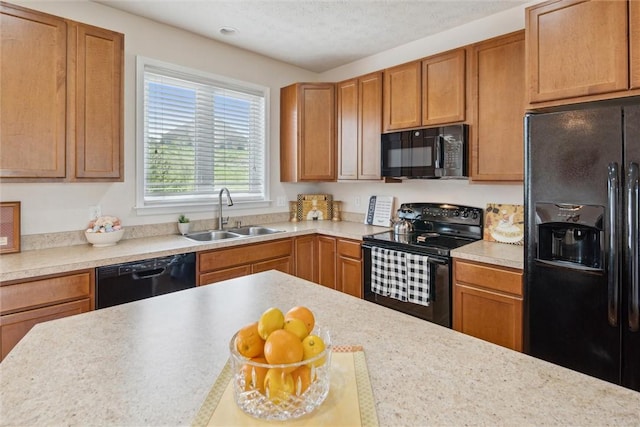 kitchen featuring light countertops, brown cabinets, a sink, and black appliances