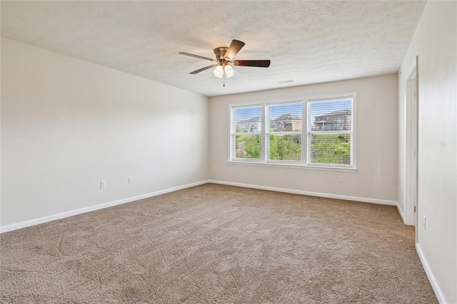 carpeted spare room featuring baseboards, a ceiling fan, and a textured ceiling
