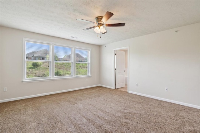 carpeted spare room with baseboards, ceiling fan, and a textured ceiling