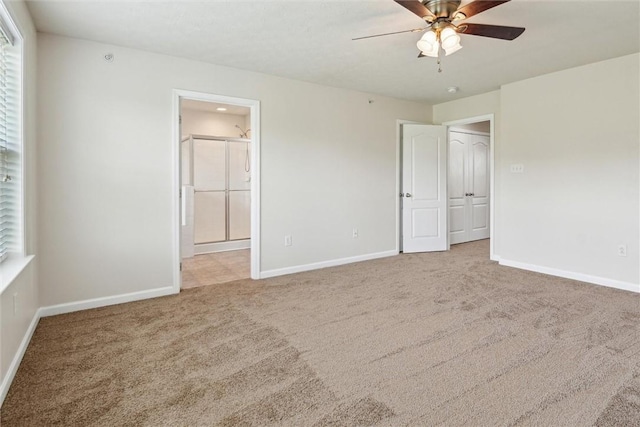 unfurnished bedroom featuring baseboards, carpet flooring, connected bathroom, and ceiling fan