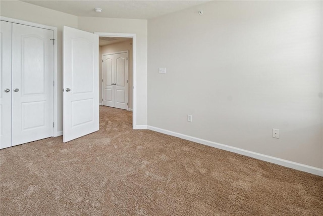 unfurnished bedroom with carpet floors, baseboards, and a closet