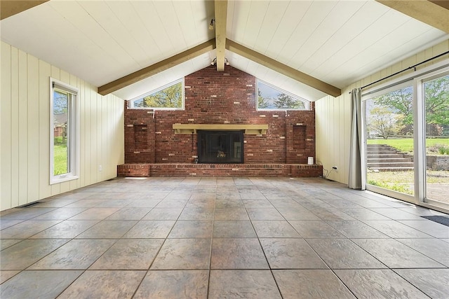 unfurnished living room featuring plenty of natural light, lofted ceiling with beams, a brick fireplace, and tile patterned floors