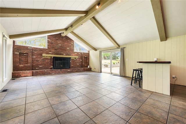 unfurnished living room with visible vents, brick wall, a fireplace, vaulted ceiling with beams, and tile patterned floors