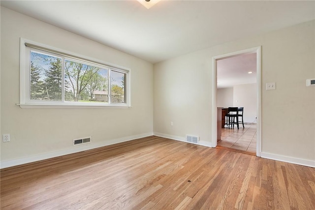 unfurnished room featuring visible vents, baseboards, and wood finished floors