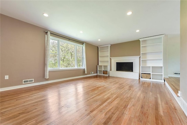 unfurnished living room featuring baseboards, a fireplace, light wood-style flooring, and visible vents