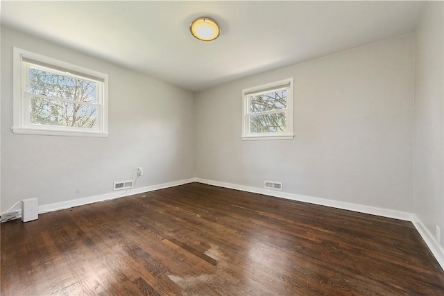 unfurnished room featuring baseboards, dark wood-type flooring, and visible vents