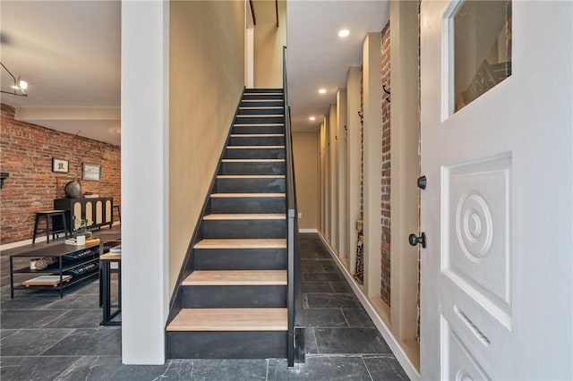 staircase with brick wall and stone tile floors