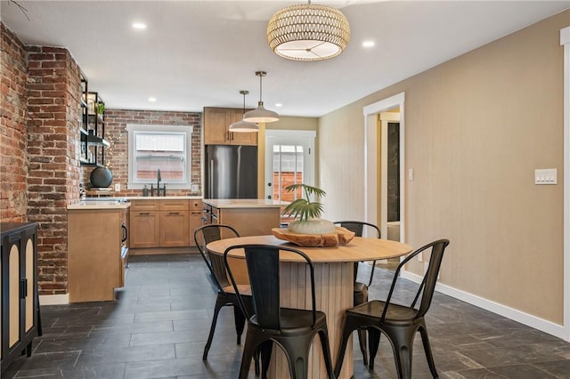 dining room featuring baseboards, recessed lighting, and brick wall