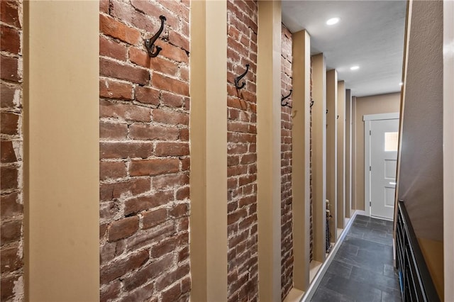 corridor with brick wall and dark stone finish floors