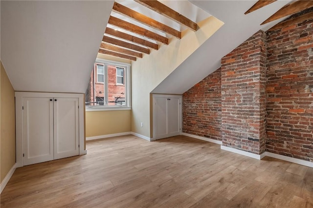 additional living space with wood finished floors, baseboards, and brick wall