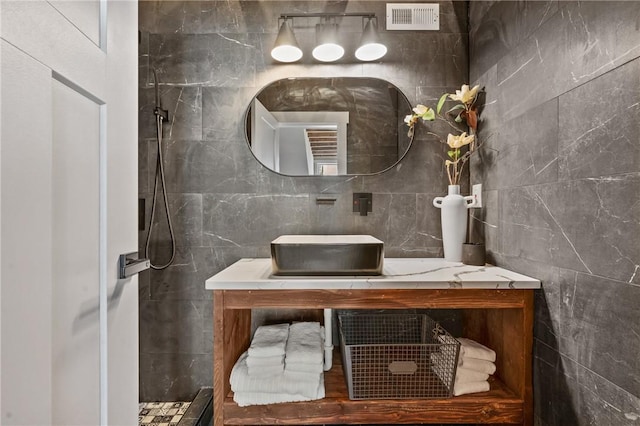bathroom with vanity, tile walls, and tiled shower