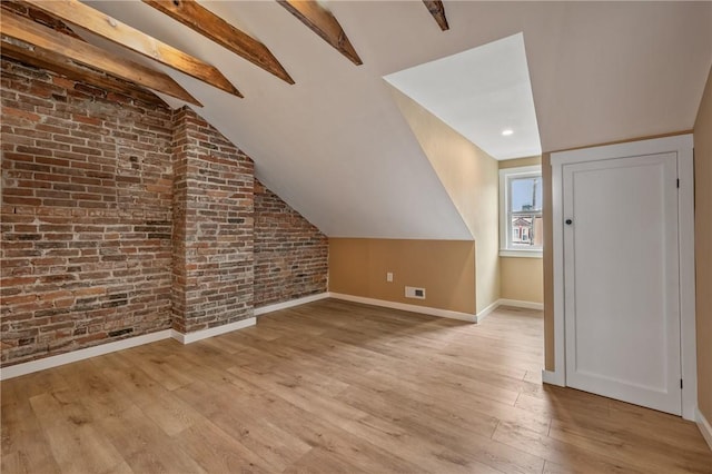 bonus room with baseboards, light wood-style flooring, and brick wall