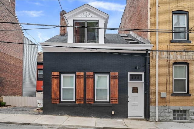 view of front of house with a chimney, brick siding, and roof with shingles