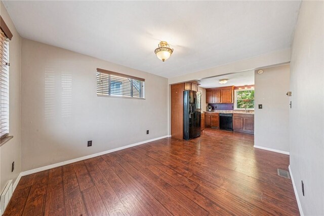 unfurnished living room featuring visible vents, baseboards, and dark wood-style floors