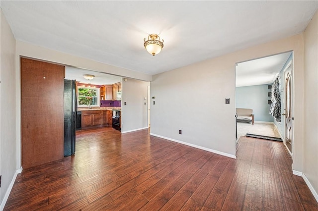 unfurnished living room with baseboards and dark wood finished floors