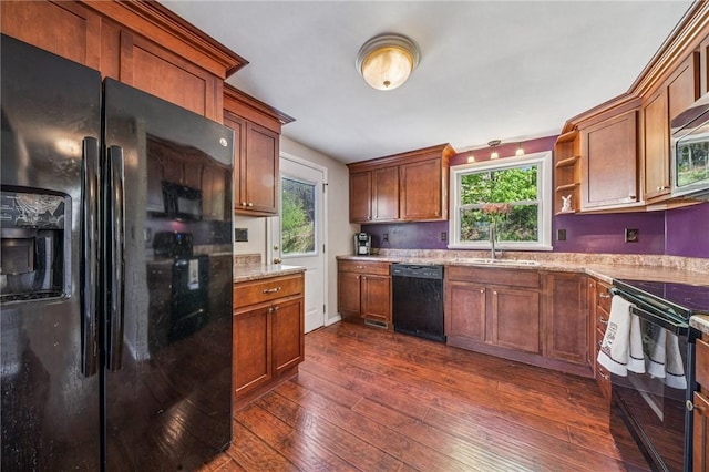 kitchen with dark wood-style flooring, plenty of natural light, a sink, and black appliances