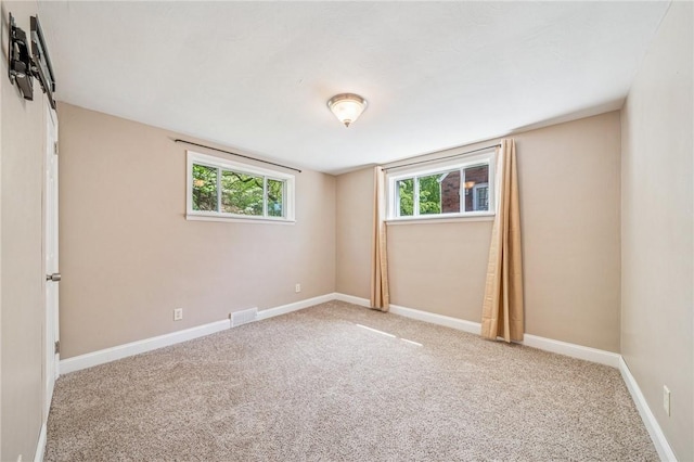 spare room with carpet flooring, baseboards, and visible vents