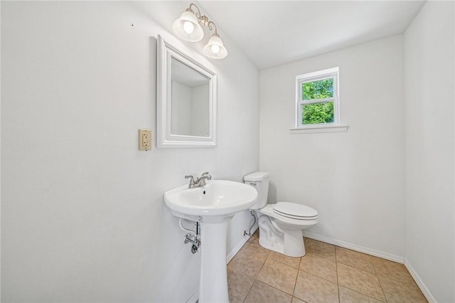 bathroom featuring a sink, baseboards, toilet, and tile patterned floors