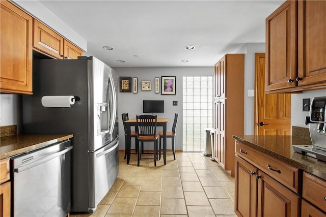 kitchen with recessed lighting, light tile patterned floors, stainless steel dishwasher, and brown cabinets