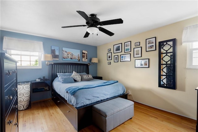 bedroom with light wood-style floors, a ceiling fan, and multiple windows