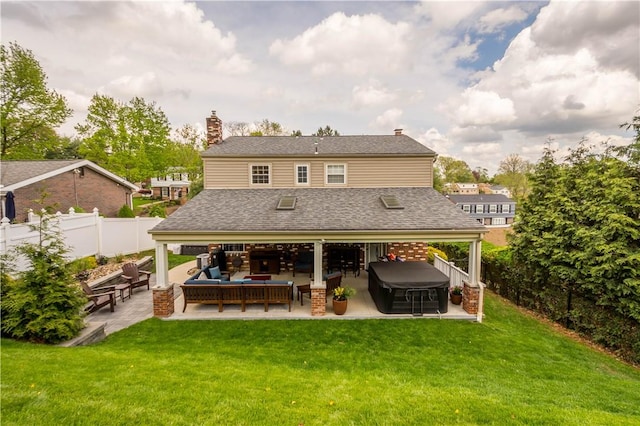 back of property with a fenced backyard, a lawn, a patio, and a hot tub